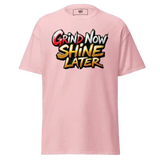 Pink t-shirt with ’Grind Now Shine Later’ graphic.